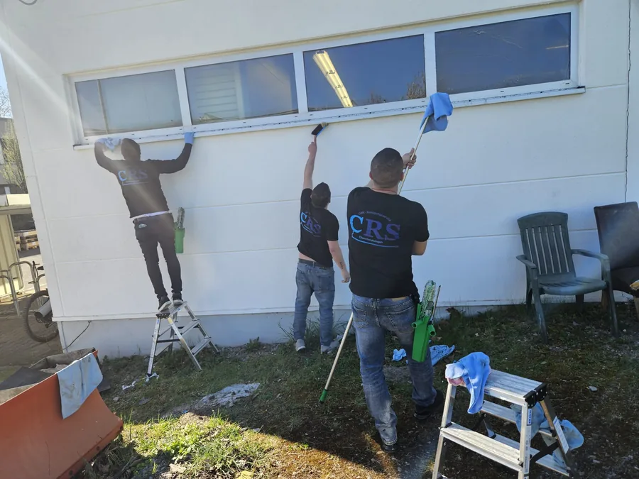 Drei CRS-Mitarbeiter reinigen die Fensterfront eines Gebäudes von außen