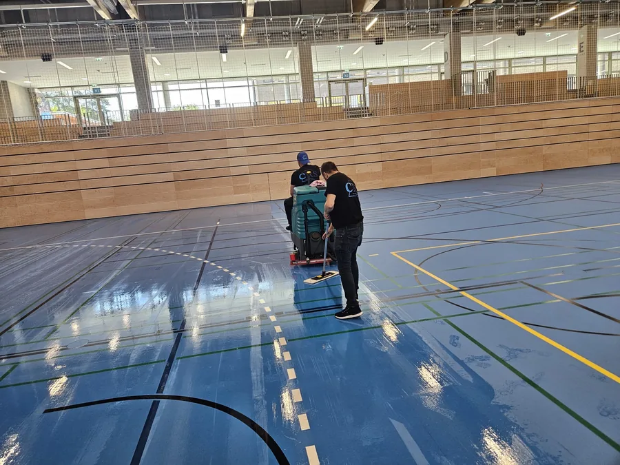 CRS-Mitarbeiter reinigen einen großen Hallenboden mit der Aufsitzmaschine